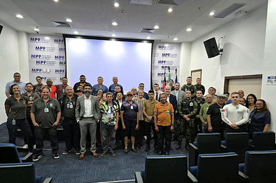 Foto mostra dezenas de pessoas em auditório, em pé, posando para foto, lado a lado, em três fileiras