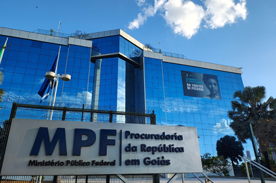 Adesivo no prédio-sede do MPF em Goiás expõe a campanha institucional contra o tráfico de pessoas. Foto: Ascom/PRGO Fachada do MPF em Goiás. O prédio de janelas azuis destaca um adesivo grande preto da campanha