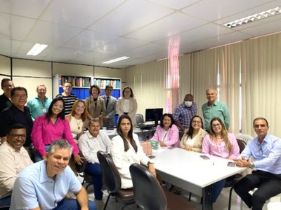 Foto de várias pessoas sentadas ao redor de uma mesa em uma reunião