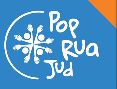 Imagem: Divulgação PopRua JUD Logomarca do programa PopRuaJud, sobre um fundo azul com um pequeno triângulo laranja no canto superior direito. À esquerda, há um desenho circular formado por quatro figuras humanas representadas por círculos (as cabeças) e mãos estendidas, formando um símbolo de união e acolhimento. À direita da imagem, está o nome “PopRuaJud” escrito em letras brancas com tipografia informal