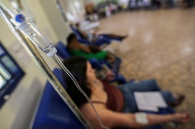 Foto ilustrativa: Marcelo Camargo/Agência Brasil Foto desfocada de um posto de saúde com uma mulher sentada em primeiro plano tomando soro