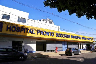 Foto: Arquivo-Agência Belém Foto da fachada do Hospital Pronto Socorro Municipal Mário Pinotti, em Belém. O prédio é branco com uma grande placa amarela na entrada, onde o nome do hospital está escrito em letras azuis. A imagem foi tirada da rua em um dia ensolarado.
