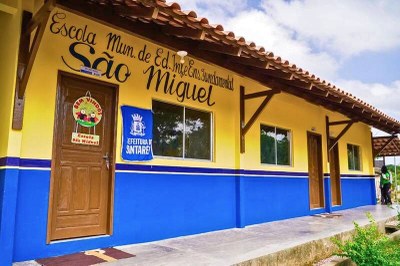 Fachada da Escola Municipal São Miguel, um prédio térreo pintado de amarelo na parte superior e azul na inferior.