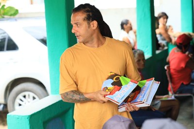 Membro da comunidade, usando uma camisa amarela, segurando um livro.