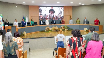 Plateia e mesa de abertura do seminário, todos em pé para execução do Hino Nacional