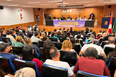 Escuta pública sobre a paralisação do Pronto-Socorro Mário Pinotti, realizada na sede do MPF em Belém, em 13/8/2025. Foto: Comunicação/MPF A imagem mostra um auditório cheio, com pessoas sentadas em poltronas azuis voltadas para um palco onde há uma mesa com oito pessoas sentadas e um homem em pé falando ao microfone. No fundo, há um painel de madeira com o texto “MPF Procuradoria da República no Pará”. Na frente da mesa, há uma faixa roxa e amarela com o texto “Escuta Pública – Desativação do Pronto Socorro Mário Pinotti - PSM da 14.