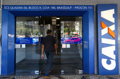 Foto ilustrativa: Fotos Públicas Foto mostra a fachada de uma agência da Caixa Econômica Federal. Um homem está na porta de vidro da agência, que está aberta