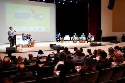 Foto mostra homem de terno cinza claro em frente a púlpito com microfone; ao fundo, há uma projeção com a expressão Construindo caminhos COP30