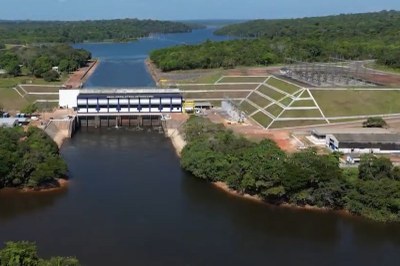 Usina hidrelétrica de Curuá-Una, localizada em Santarém (PA). Foto: Eletrobras Eletronorte/Divulgação foto aérea da hidrelétrica de Curuá-Una, com a barragem, o reservatório de água cercado por mata e o rio correndo abaixo da estrutura.