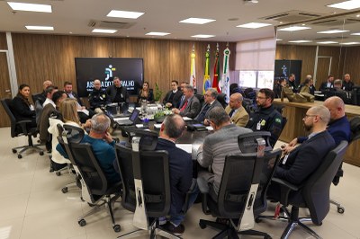 Foto mostra as pessoas participantes da reunião em volta de uma mesa 