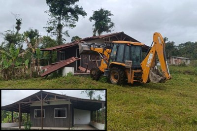 Foto: Polícia Federal Imagem de uma retroescavadeira demolindo uma casa de madeira. O veículo levanta parte do telhado já arrancado. No canto inferior esquerdo, em destaque, aparece uma foto da mesma casa antes da demolição, com paredes de madeira e varanda coberta.