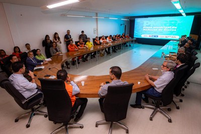 Foto tirada durante a reunião com os participantes sentados em circulo na mesa.
