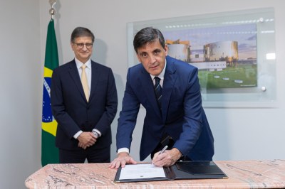Foto do novo PGT assinando o documento de posse com o PGR ao fundo