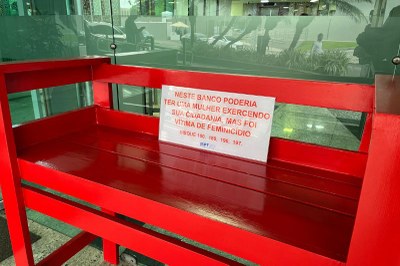 Fotos: MPF Foto de um banco vermelho mostrando a frase Neste banco poderia ter uma mulher exercendo sua cidadania, mas foi vítima de feminicídio disque 100, 180, 190, 197