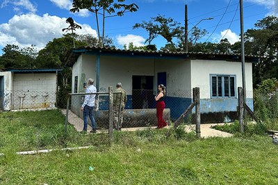 Três pessoas observam um prédio de alvenaria em condições precárias de conservação