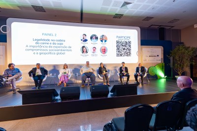 Foto de palestrantes sentados em cadeiras sobre o palco de um auditório.