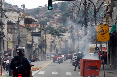 Foto: Fernando Frazão/Agência Brasil Foto de uma comunidade no Rio de Janeiro durante operação policial, com motos e carros em meio à fumaça