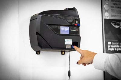 Foto mostra uma pessoa registrando presença em ponto eletrônico