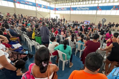 Fotos: Comunicação MPF Um grande público de costas, sentado em cadeiras brancas num ginásio, assiste a um painel de pessoas e uma tela ao fundo, sob faixas com a palavra "Castanhal"