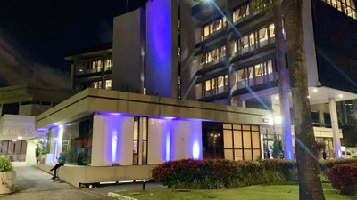 Foto: NMSG/PRPE foto do edifício-sede iluminado na cor roxa.