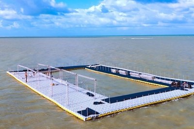 Instalação de piscina flutuante para a competição esportiva Aquarace 2025, no mar da praia do Bessa, em João Pessoa (PB). Foto: Governo da Paraíba. Fotografia de uma estrutura retangular flutuante sobre o mar, nas cores branca e preta, com operários trabalhando na montagem.