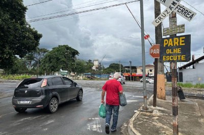 Foto: Divulgação Assembleia Legislativa de Minas Gerais Foto mostra um carro e um pedestre passando por uma linha de trem que passa pela cidade, a foto mostra também as placas informando sobre o cruzamento