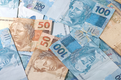 Foto ilustrativa: Canva Foto mostra diversas cédulas de 50 e 100 reais dispostas de forma desorganizada