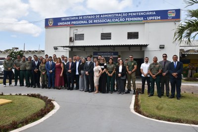 Visita técnica ao Complexo Penitenciário de Pedrinhas, em São Luís (MA), em 9/10/2025. Foto: Monteles/Seap. Autoridades do sistema de justiça em visita técnica ao Complexo Penitenciário de Pedrinhas, em São Luís (MA). Estão todos em pé, de frente para a câmera no pátio de uma unidade prisional, em frente a um prédio em formato retangular com uma placa azul no topo com o nome da unidade (UPFEM).