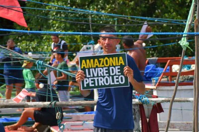 Foto: Divulgação/Rede de Trabalho Amazônico GTA Homem de camiseta azul segura cartaz verde com os dizeres 'Amazônia Livre de Petróleo' em letras amarelas e brancas