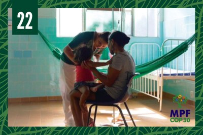 Foto mostra uma profissional de saúde atendendo a uma criança indígena que está no colo da mãe 