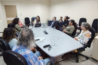 Foto da reunião mostra uma mesa branca e participantes sentados ao redor 