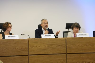 Foto: Comunicação/MPF imagem de mesa larga com um homem ao centro e duas mulheres à esquerda e à direita. o homem segura o microfone.