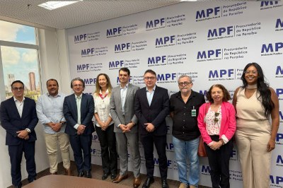 Reunião Rede Paraibana de Combate à Desinformação Imagem mostra dez pessoas em pé, lado a lado, em sala de reunião do Ministério Público Federal na Paraíba. Estão vestidas formalmente, sugerindo reunião oficial. Há mesa à frente e janela ao fundo com vista urbana.