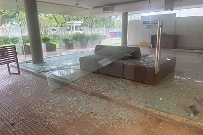 Foto: Administração PRR4 Imagem do foyer da PRR4 visto de fora com a porta de vidro caída sobre um sofá e inúmeros cacos espalhados pelo chão e pelo próprio móvel.