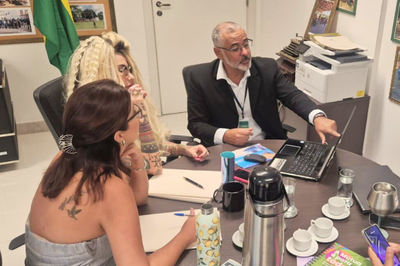 Fotos: Comunicação MPF Foto de três pessoas em uma reunião de trabalho em um escritório, com um homem apontando para o laptop e uma mulher de costas anotando em um caderno.