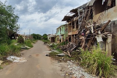 Foto de uma rua com casas devastadas em ambos os lados.