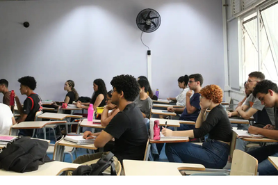 foto mostra estudantes sentados em sala de aula enquanto fazem uma prova