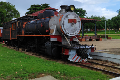 Foto: Iphan Foto de uma locomotiva a vapor preta e branca (número 18) da Estrada de Ferro Madeira-Mamoré, exposta em um parque.