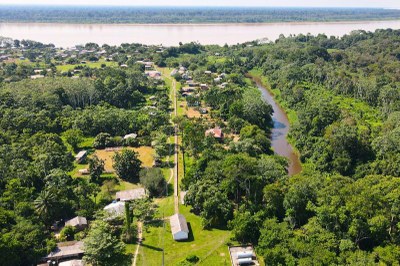 Foto aérea de uma das comunidades visitadas mostra a vegetação verde, casas e o rio ao fundo