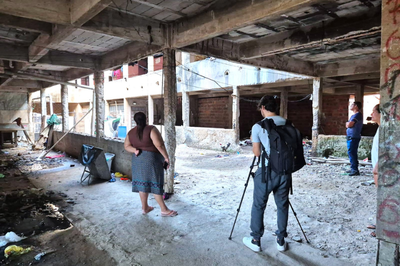 Foto mostra dois homens e uma mulher em prédio em construção