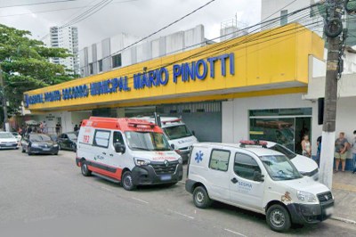Fachada do Hospital Pronto Socorro Municipal Mário Pinotti. Letreiro azul sobre amarelo e, na rua, ambulância do Samu e veículos da Secretaria Municipal de Saúde de Belém.