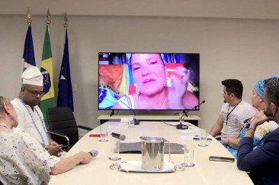 Foto: Comunicação/MPF Foto mostra mesa de debate do podcast com cinco pessoas sentadas ao redor olhando para um telão enquanto outra participante fala