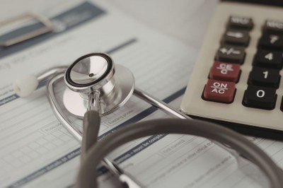 Foto ilustrativa: Canva Foto mostra um estetoscópio em cima de um formulário e uma calculadora ao lado