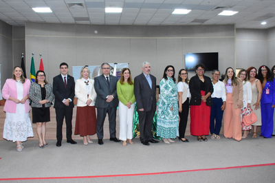 Fotos: TJPB e MPF Foto de um grupo de aproximadamente 15 pessoas, incluindo homens e mulheres em trajes formais, alinhados para uma foto em um evento institucional, com bandeiras brasileiras ao fundo.