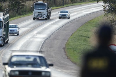 Foto de um trecho de rodovia mostra carros passando por uma curva