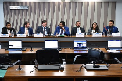Fotos: Jefferson Rudy/Agência Senado Imagem mostra seis homens e uma mulher sentados atrás de uma bancada. Em frente à bancada, duas mesas compridas, cadeiras e notebooks.