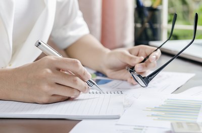 Fonte: Stock Photos Pessoa segurando caneta e óculos enquanto escreve.