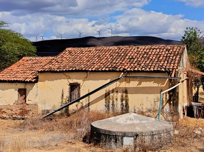 Casa típica do sertão nordestino com torres de eólicas ao fundo