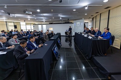 seminriominerao.jpg Esta imagem registra o ambiente do seminário realizado em Brasília:
Composição: A foto mostra um auditório com uma mesa de honra composta por cinco autoridades à direita e uma plateia atenta à esquerda.
Mesa Diretora: Os integrantes estão sentados atrás de uma mesa coberta com tecido preto, equipada com microfones e placas de identificação. Um dos participantes destaca-se usando um terno azul vibrante.
Plateia e Ambiente: Os espectadores ocupam mesas organizadas em fileiras, também cobertas de preto. Ao fundo, há telas de projeção exibindo participantes de forma remota, indicando o formato híbrido do evento.
Iluminação e Design: O espaço é amplo, com iluminação embutida no teto e janelas ao fundo cobertas por persianas claras, conferindo um tom profissional e institucional à reunião.