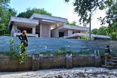 Foto: fiscalização Semma Santarém - fev/2024 Agentes da Semma fiscalizam obra de casa moderna em concreto bruto, cercada por tapume metálico e vegetação em Alter do Chão.